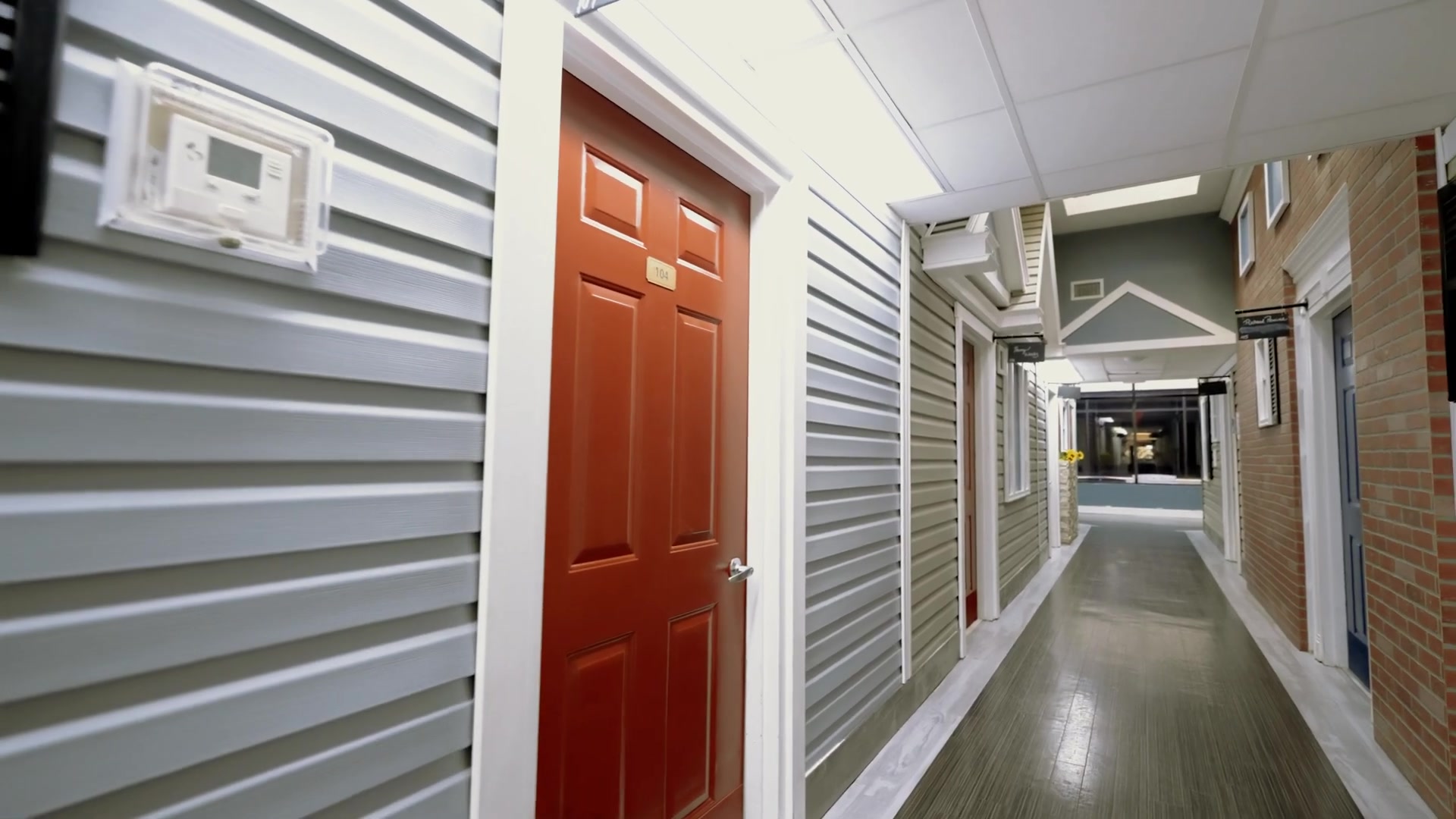 Welcoming colonial-style hallway with colorful doors at Colonial Gardens assisted living and memory care community in Lauderhill FL