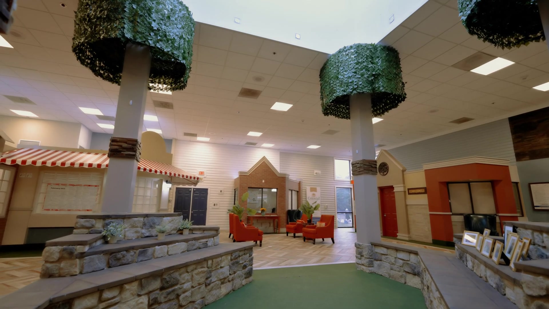 Spacious grand lobby at Colonial Gardens Residences assisted living facility in Lauderhill FL featuring decorative tree-trunk pillars and elegant seating areas